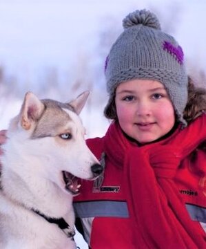 A girl makes friends with a husky sled dog