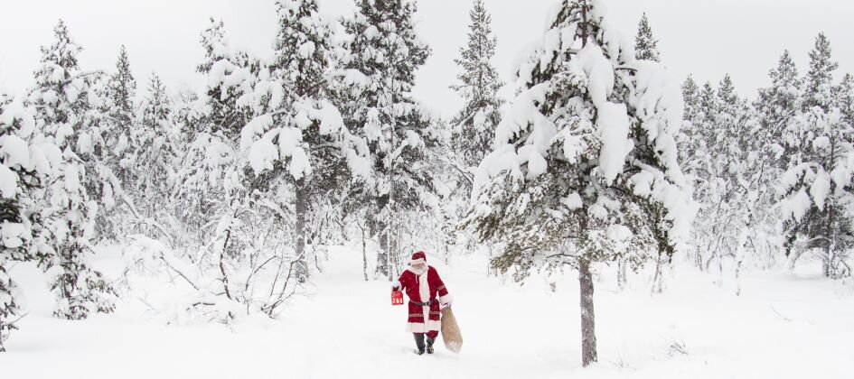Santa in a snow-covered forest with a bag of gifts