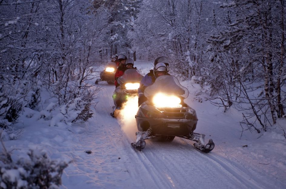 A line of adventurers driving snowmobiles