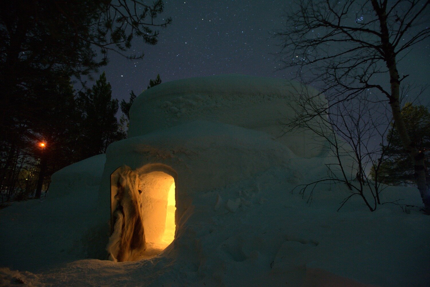 The door of a snow igloo illuminated by candlelight
