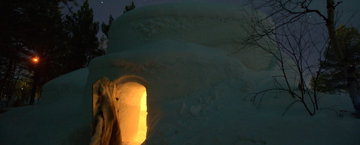 The door of a snow igloo illuminated by candlelight