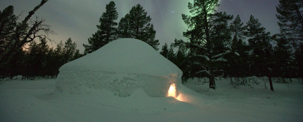 A snow igloo beneath the Northern Lights