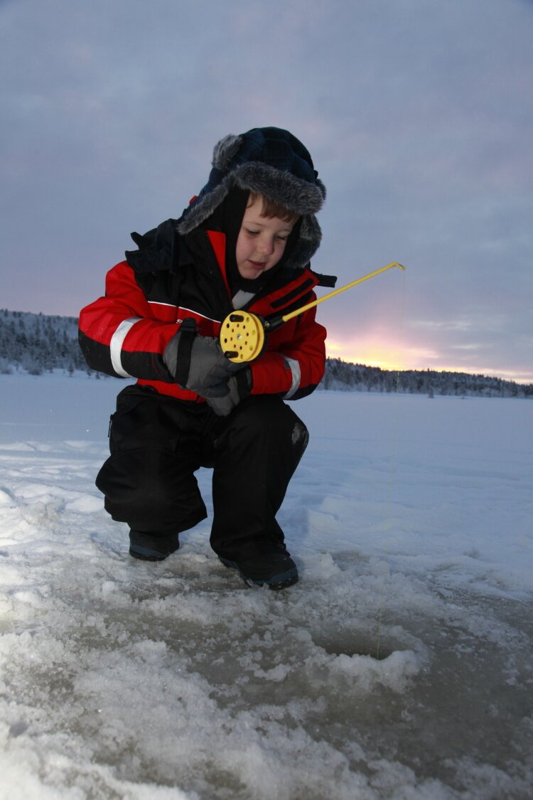 A boy tries his hand at Arctic ice fishing