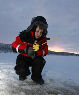 A boy tries his hand at Arctic ice fishing