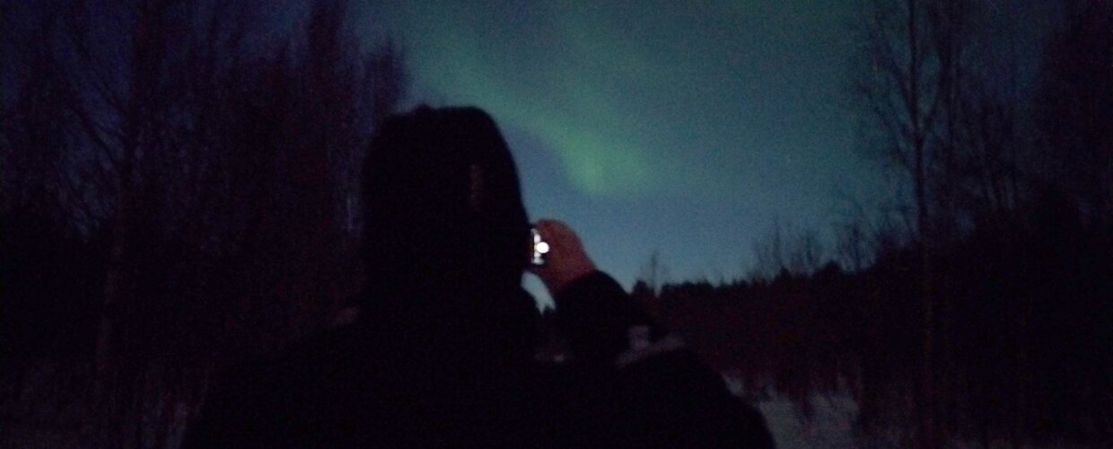 A man taking a photo on his phone of the Northern Lights