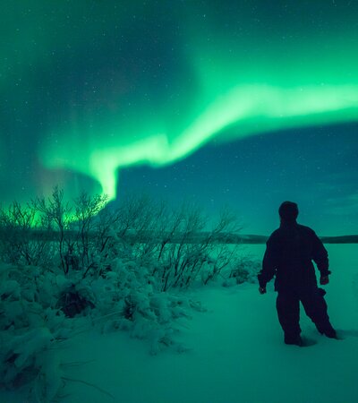 Man walking in the snow beneath the Northern Lights