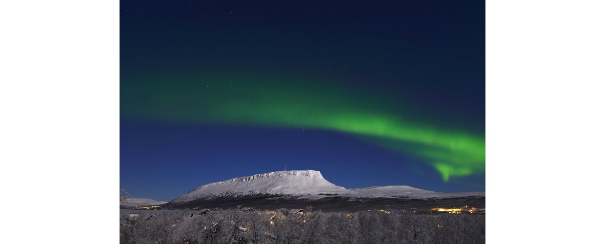 A view of Kilpisjarvi with Saana Fell on the horizon and the Northern Lights overhead