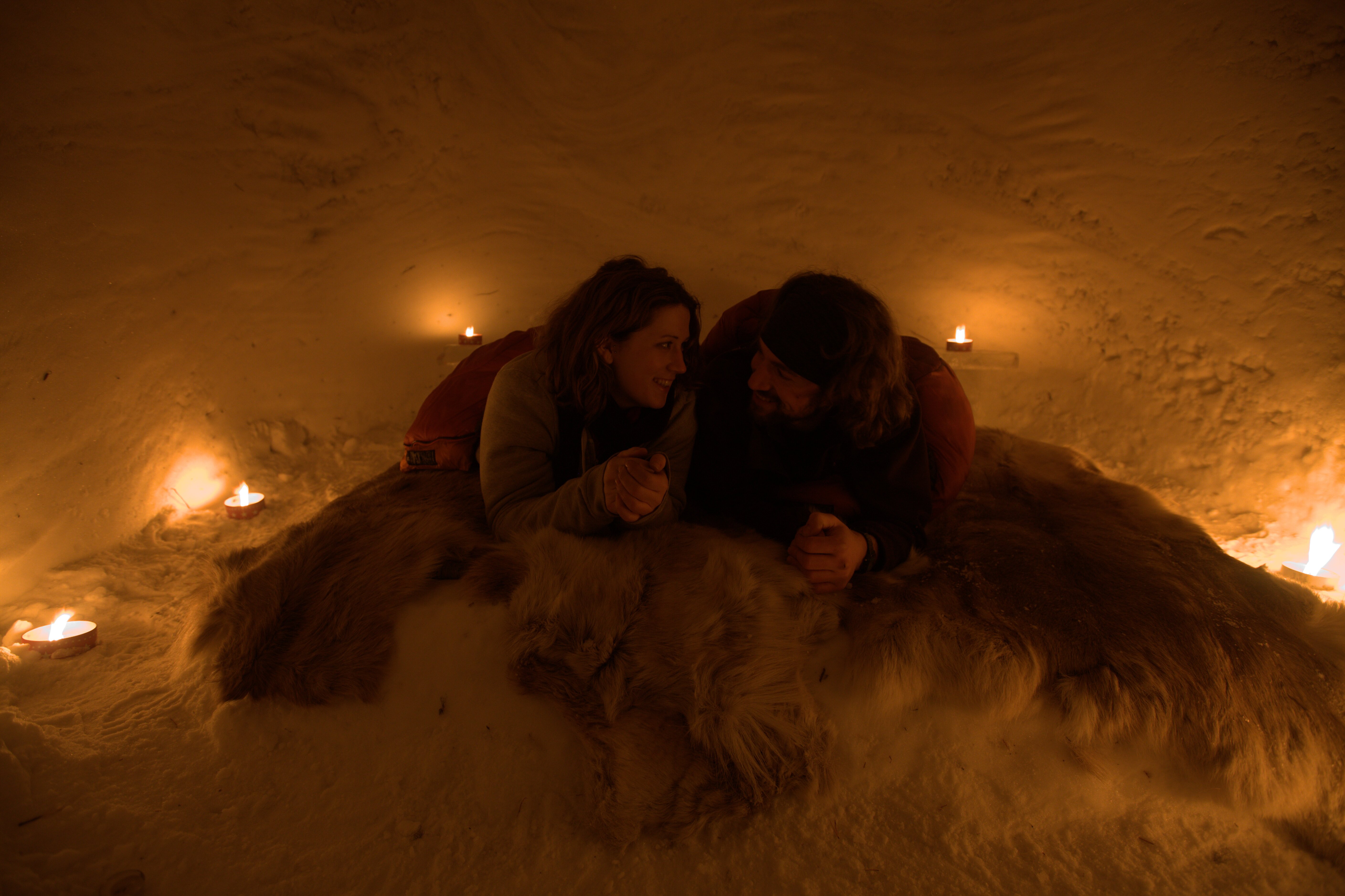 A couple snuggling together in a snow igloos