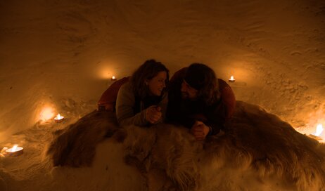 A couple snuggling together in a snow igloos