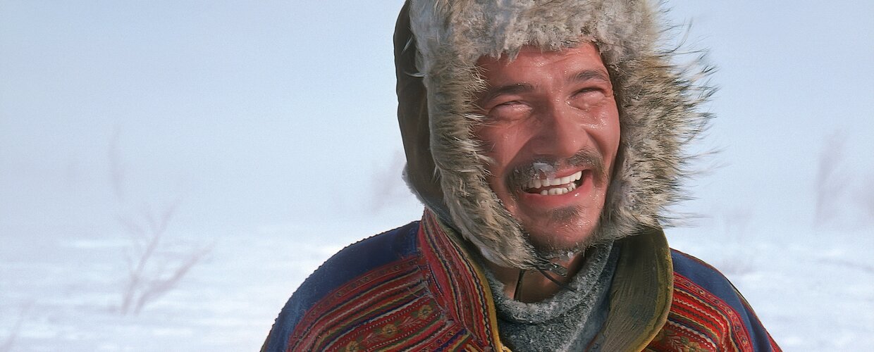 A Sami man in traditional dress outside in the frozen tundra of Finnish Lapland